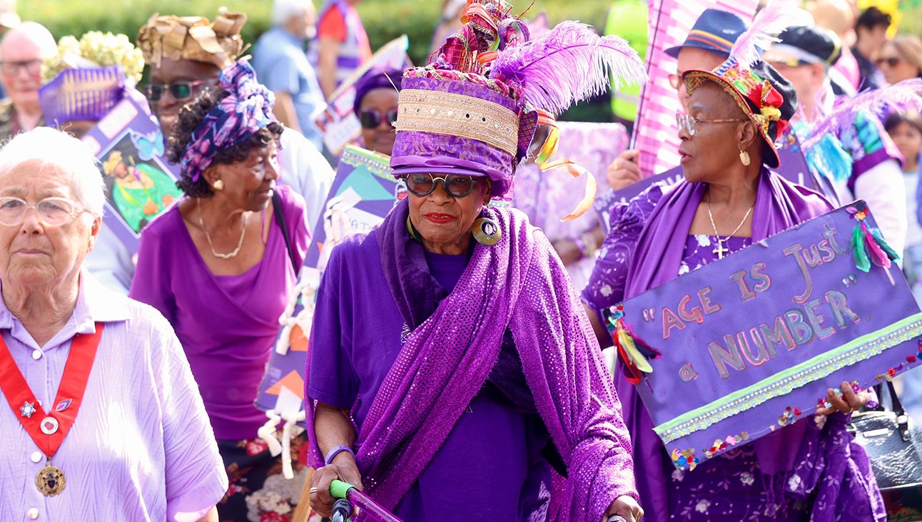 Three older black woman dressed in purple, as part of the Purple parade