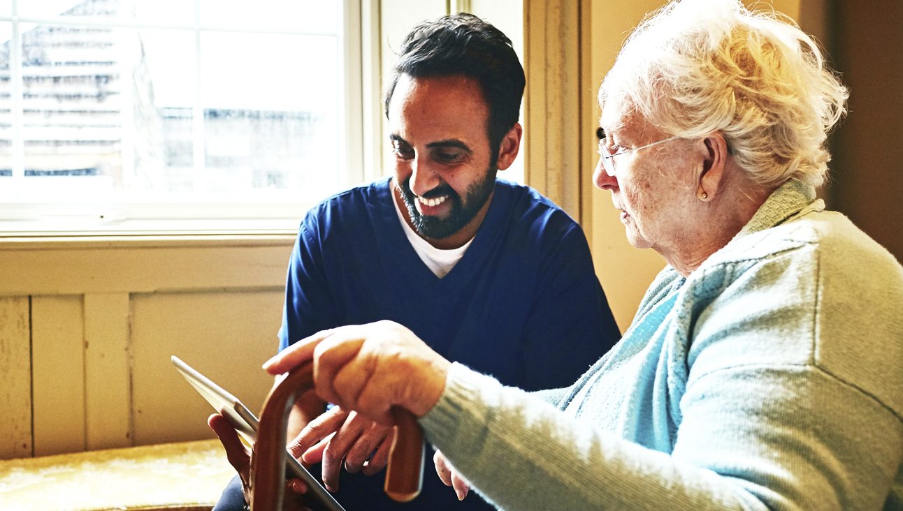 An old white women being helped by a male nurse