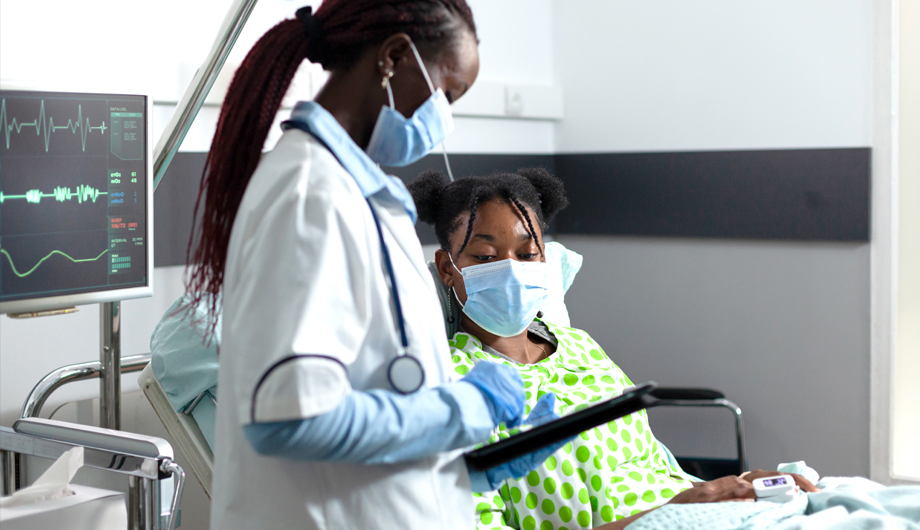 Black Woman in Hospital Bed with Doctor Assessing