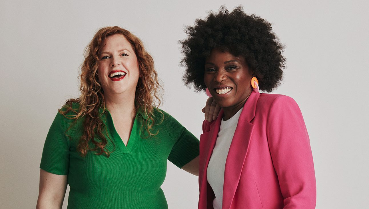Black woman and white woman in front of white backdrop smiling