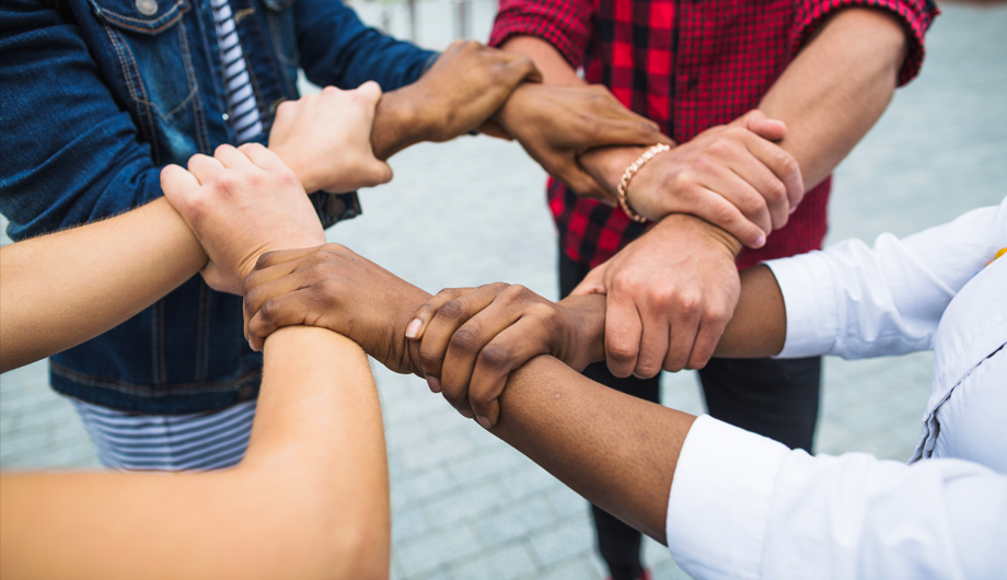 Group of diverse people linking arms together to show partnership and support