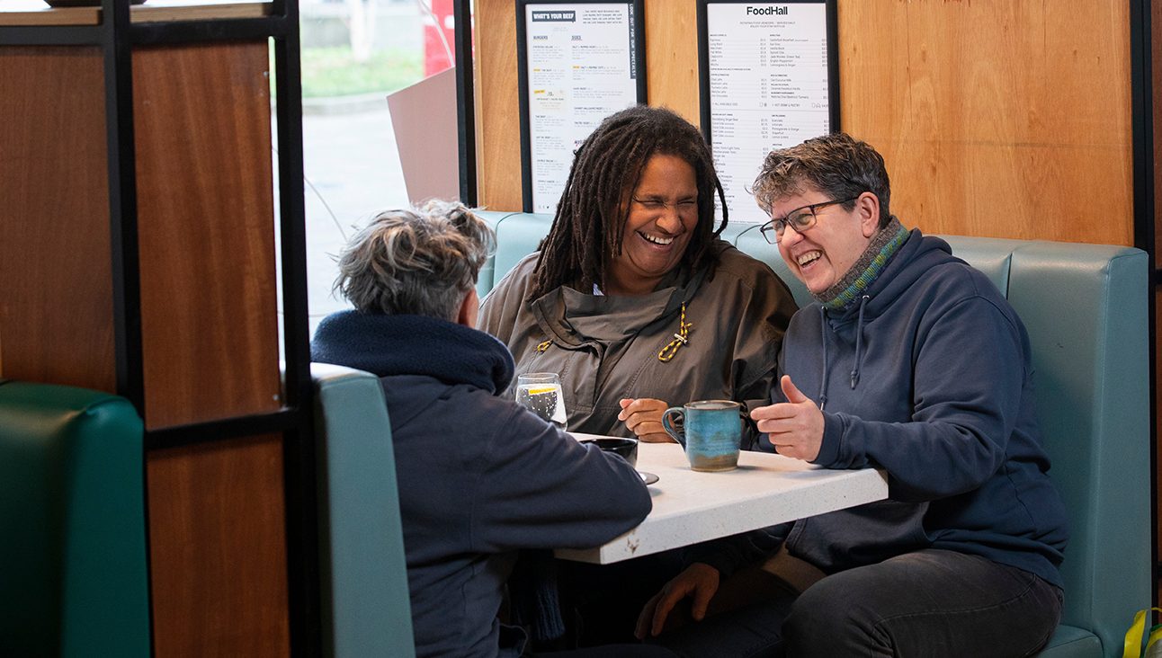 Three woman in a cafe booth laughing and talking