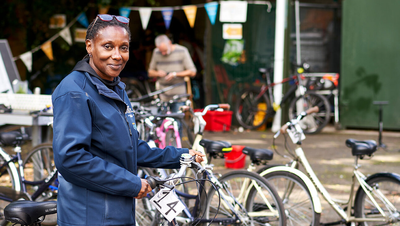 A black woman standing by a bicycle surrounded by other bicycles