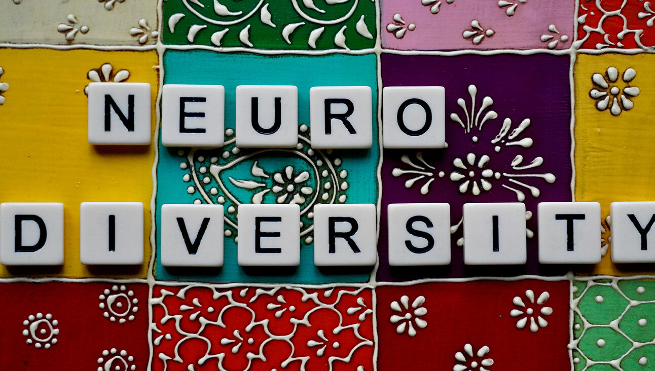 White tiles that spell out 'neurodiversity' laid on top of multicoloured, patterned tiles